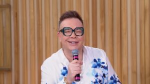 Jornalista Felipeh Campos sorrindo em estúdio de TV com banner de notícia urgente sobre saúde.