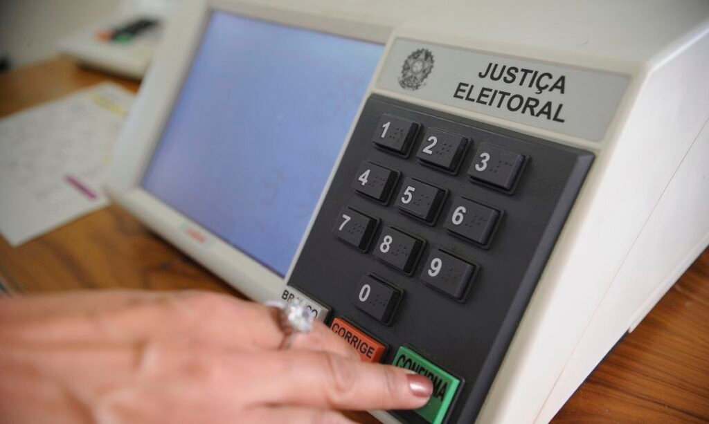 Urna eletrônica brasileira com eleitor confirmando o voto no teclado